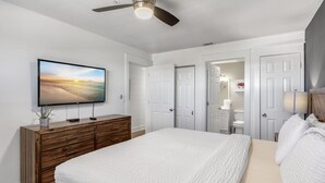 A bedroom with a bed, a wooden dresser, a television mounted on the wall, and a ceiling fan. - Crystal Sands 314A - Gulf Front, Free Beach Service, Heated Pool, Sleeps 8 (Destin)