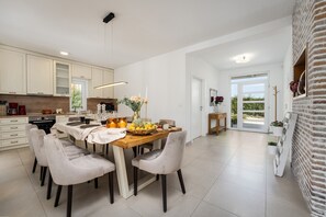 A modern kitchen with white cabinets, a wooden dining table, and a large window. - Villa with pool in quiet location, 4 bedrooms, 5 bathrooms, panoramic sea views (Labinci)