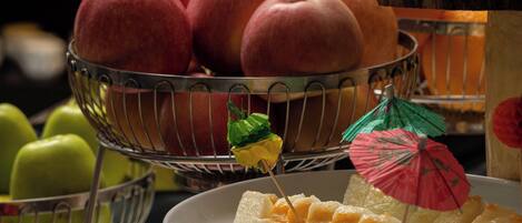 Diversa variedad de frutas y postres a la vista, como manzanas, plátanos y sandía, dispuestas en bandejas y platos.