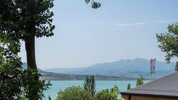 A grassy area with a picnic setup, a gazebo, and a view of a lake and mountains.