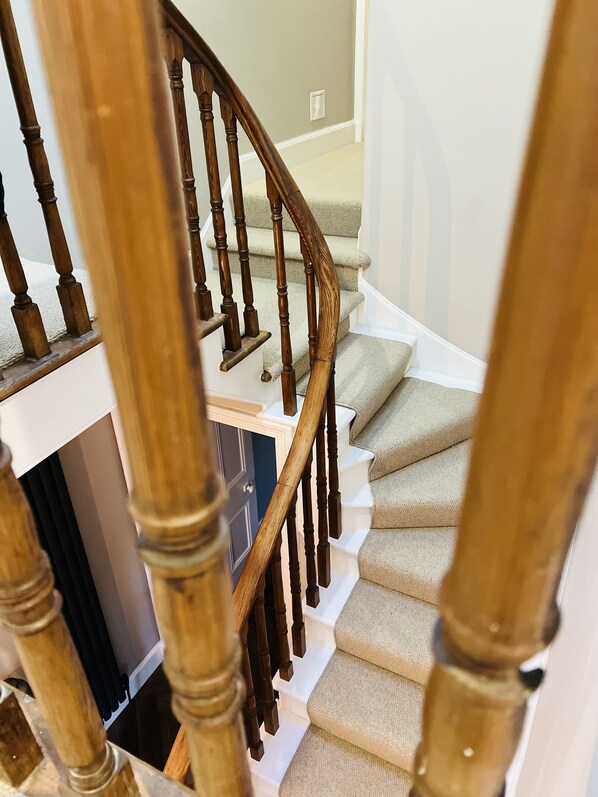 A wooden staircase with beige carpeted steps and a white wall in the background. - St Duthus Villa Guesthouse (Tain)
