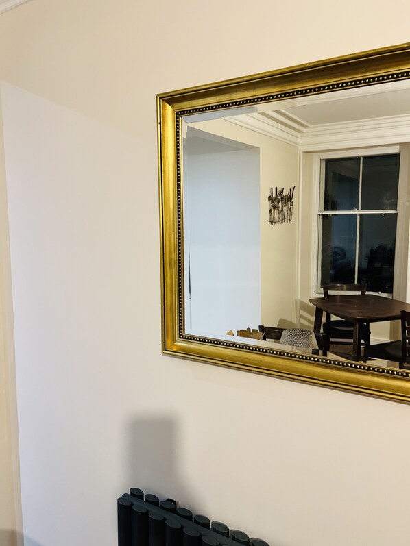 A room with a large mirror, a radiator, and a window with a view of the outside. - St Duthus Villa Guesthouse (Tain)