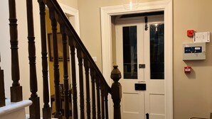 A staircase with wooden balusters and white handrails, leading to a door with a glass panel. - St Duthus Villa Guesthouse (Tain)