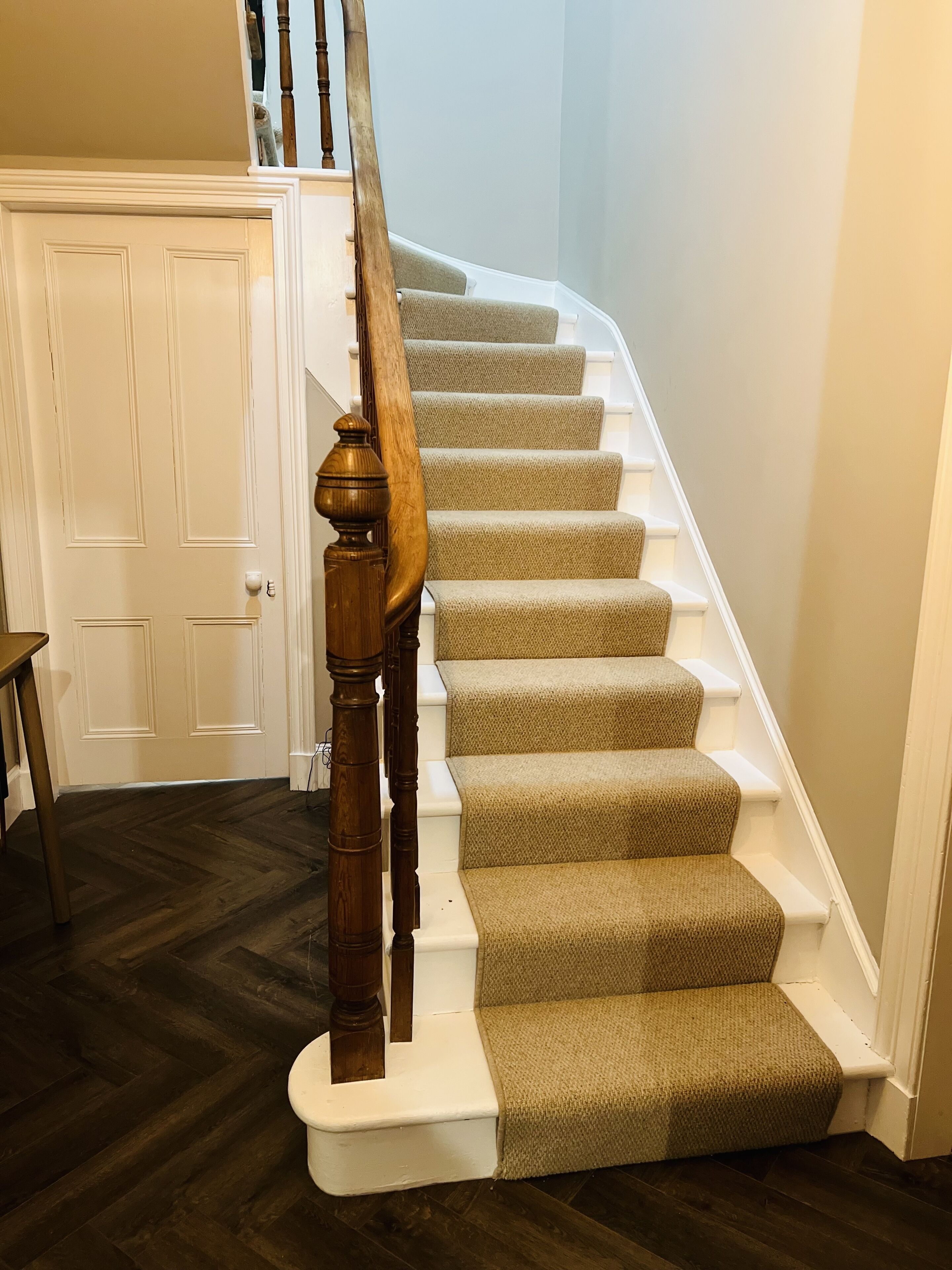 A staircase with wooden balusters and beige carpeted steps.