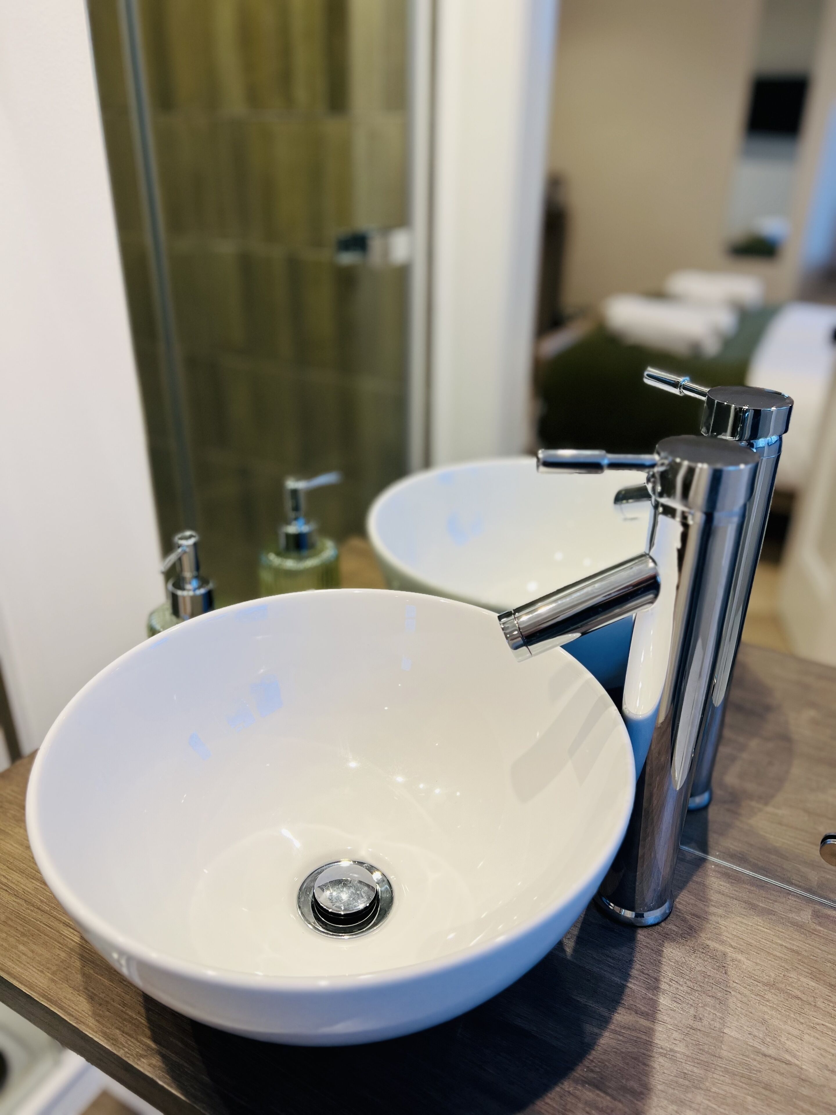 A bathroom with two white sinks, a chrome faucet, and a mirror reflecting the room.