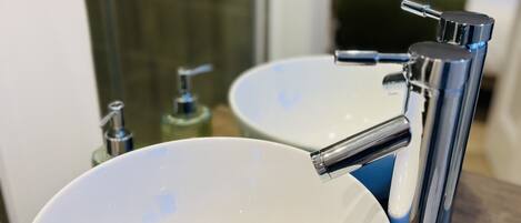A bathroom with two white sinks, a chrome faucet, and a mirror reflecting the room.