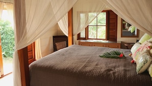 Une chambre à coucher avec un grand lit, une commode en bois et une fenêtre avec des rideaux.
