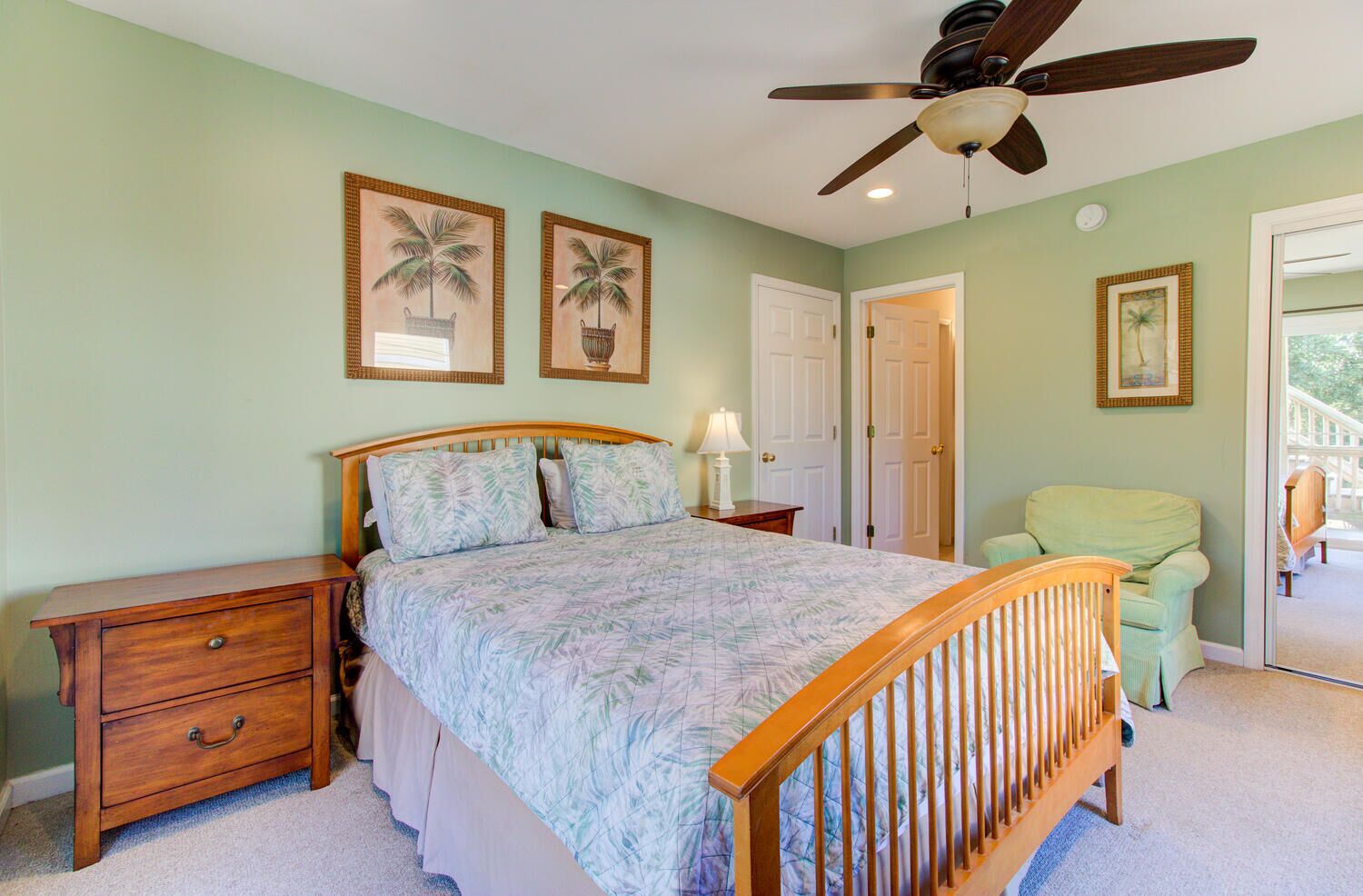 A bedroom with a bed, nightstands, a wooden chair, a ceiling fan, and two framed pictures on the wall.