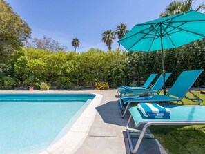 Zona de piscina con sillas de descanso y una sombrilla grande.