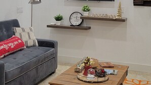 Un soggiorno moderno con un divano grigio, un tavolino in legno e un televisore a schermo piatto fissato al muro.