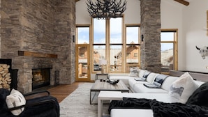 Un salón amplio con chimenea de piedra, ventanas grandes y una zona de estar acogedora.