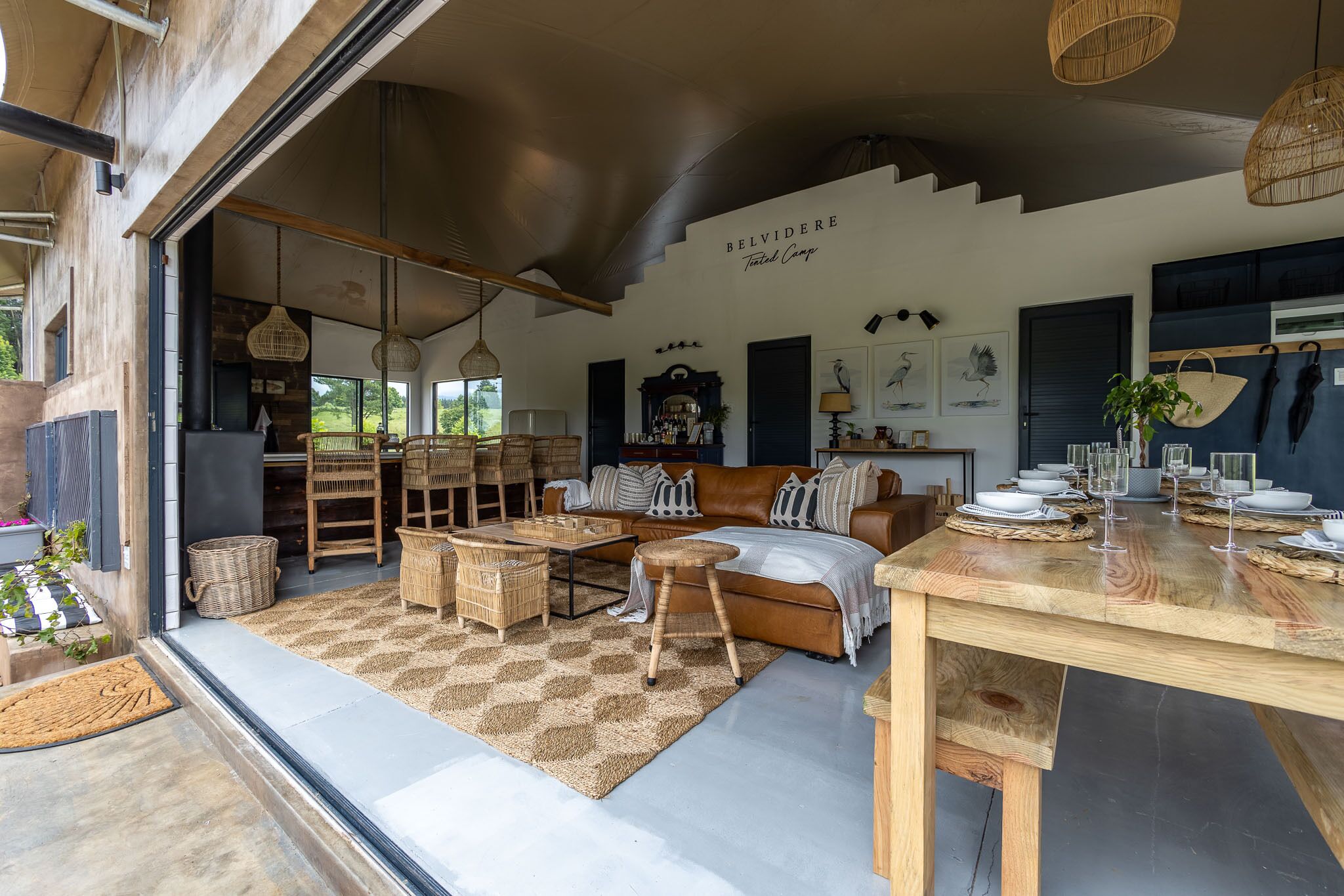 Un salon moderne avec un canapé, une table basse et une table à manger. On y trouve également un panier en osier et un luminaire suspendu.