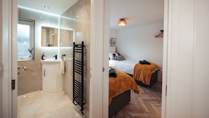 A modern bathroom with a glass shower enclosure, a vanity with a mirror, and a towel rack. - Exquisite 6 Bedroom Luxury Home (Manchester)