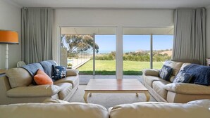 A living room with two sofas, a coffee table, and a view of the outdoors. - Encounter Blue Victor Harbor Retreat: Secluded Pool (Waitpinga)