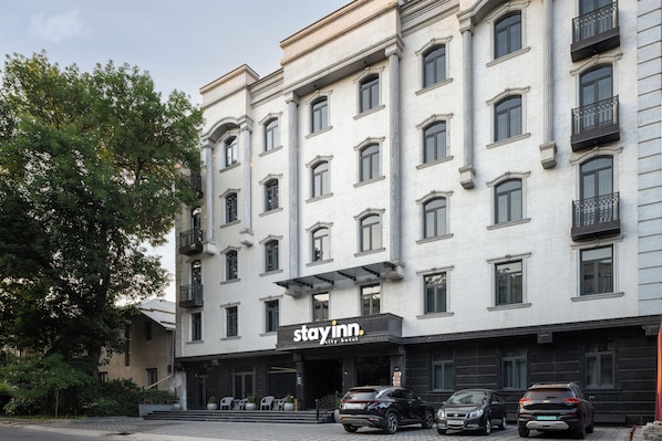 A multi-story hotel with a 'Stay Inn' sign, featuring a classic architectural style with symmetrical windows and balconies.
