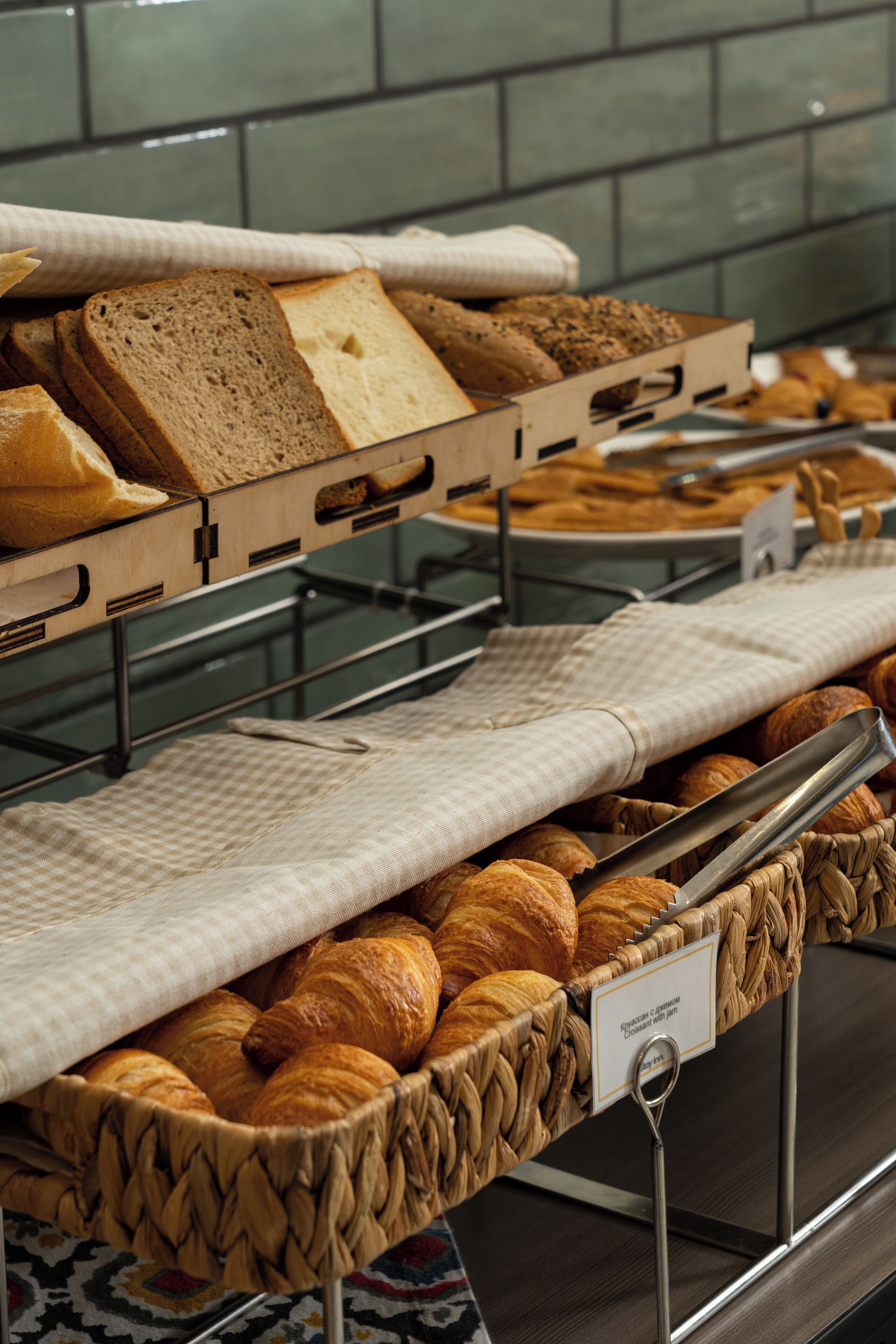 A breakfast buffet with bread, pastries, and croissants.