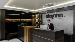 A reception desk with a modern design, a laptop, and a framed picture on the wall. - StayInn City Center (Tashkent)