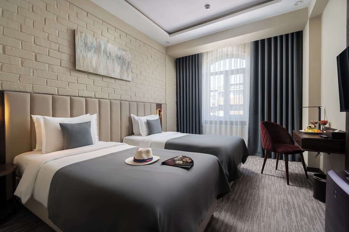 Ein Hotelzimmer mit zwei Betten, einem Schreibtisch, einem Stuhl und einem Fernseher.