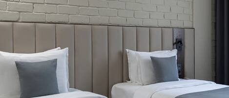 A hotel room with two beds, a brick-patterned wall, and a ceiling light fixture.