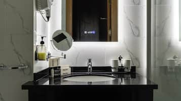 A modern bathroom with a black marble sink, a round mirror, and a digital display above the mirror.