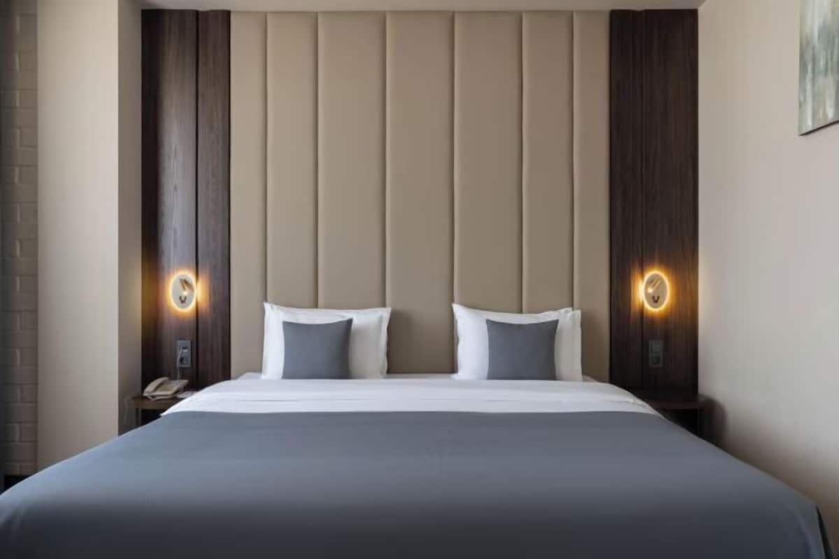 Ein Hotelzimmer mit einem großen Bett, zwei Nachttischen und Wandleuchten.