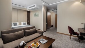 A hotel room with a bed, a sofa, a dining table, and a chair. - StayInn City Center (Tashkent)
