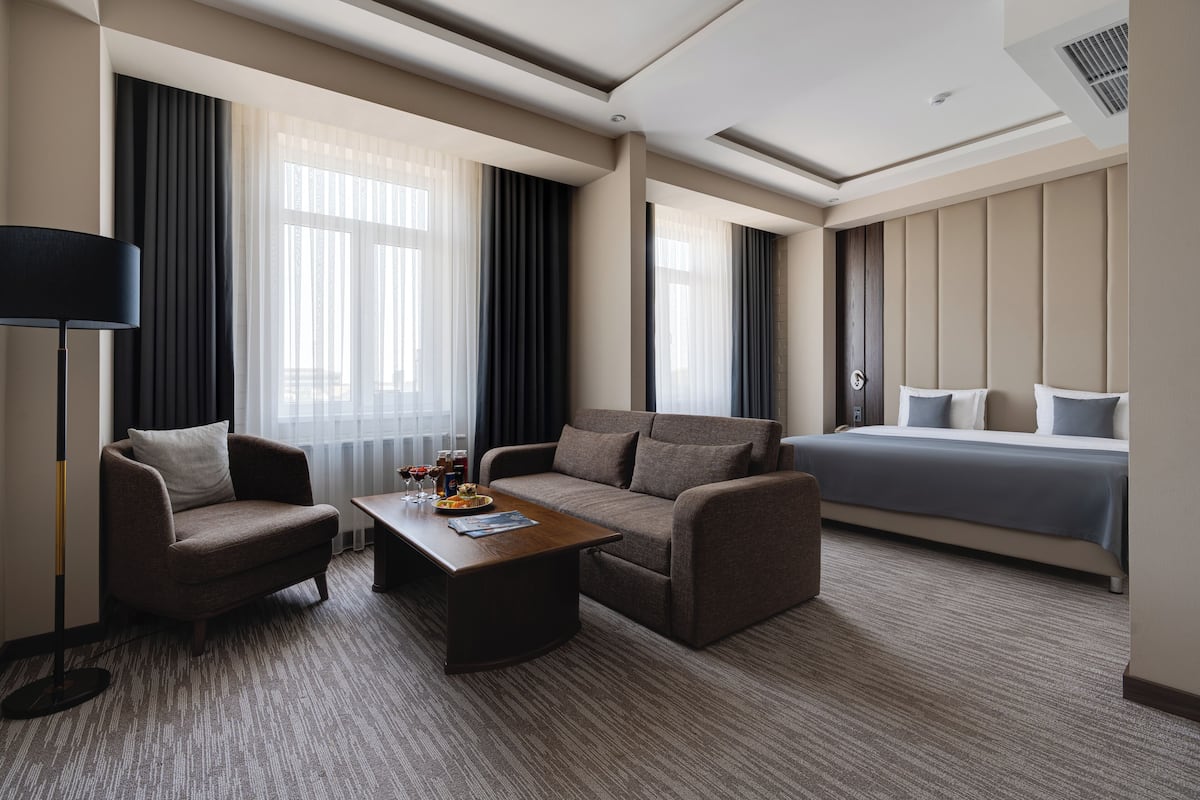 Ein Hotelzimmer mit einem Bett, zwei Sesseln, einem Couchtisch und einer Stehlampe.