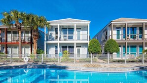A pool area with a clear blue pool, white buildings with balconies, and palm trees. - ⛱️By Beach-Waterfront Villa- Pool-4BR Destiny Beach Villas 11-Beach Oasis (Destin)