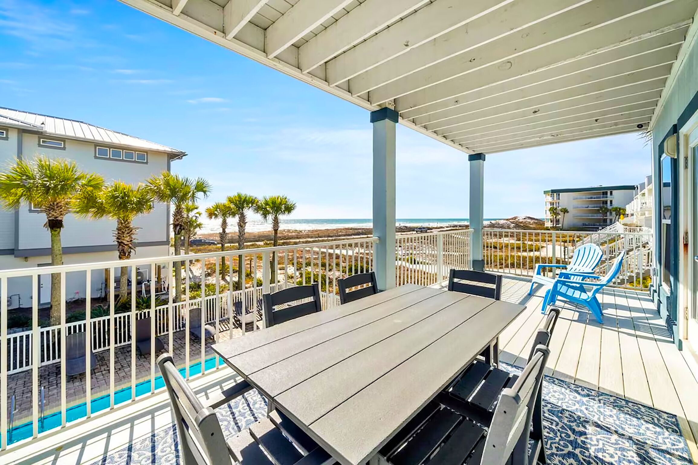 A covered outdoor patio with a pool, seating, and a view of the beach.