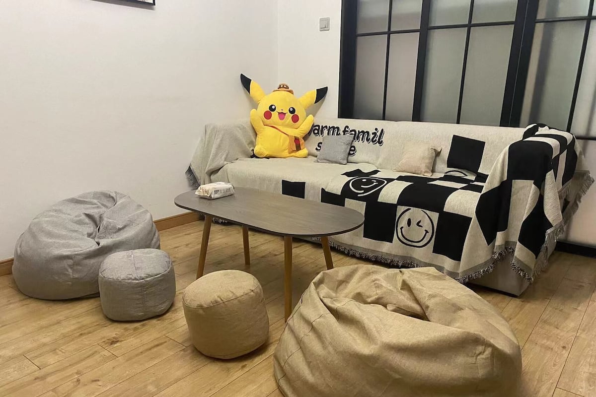 A cozy living room with a sofa, bean bags, and a small table.