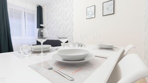 Mesa de jantar posta com pratos, copos e talheres, com um jogo americano com ícones.