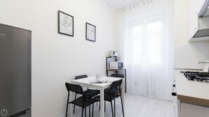 Uma cozinha compacta com mesa, cadeiras, geladeira, micro-ondas e fogão a gás.