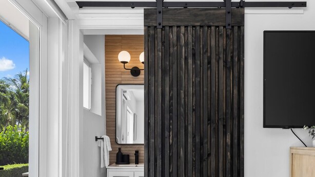 A modern bathroom with a sliding barn door, a white vanity, and a large mirror.