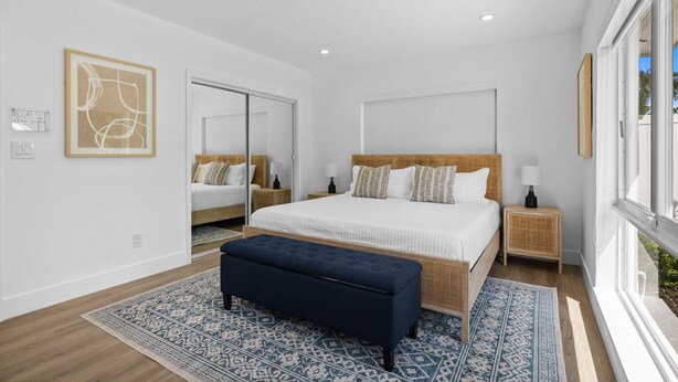 A modern bedroom with a large bed, bedside tables, a bench, and a large window. - Modern Coastal Pool Home in Lauderdale-By-The-Sea! Walking distance to the Beach (Lauderdale-by-the-Sea)