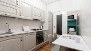 A compact kitchen with white cabinets, a gas stove, a sink, and a microwave. - Uguzzone 21 (Milan)