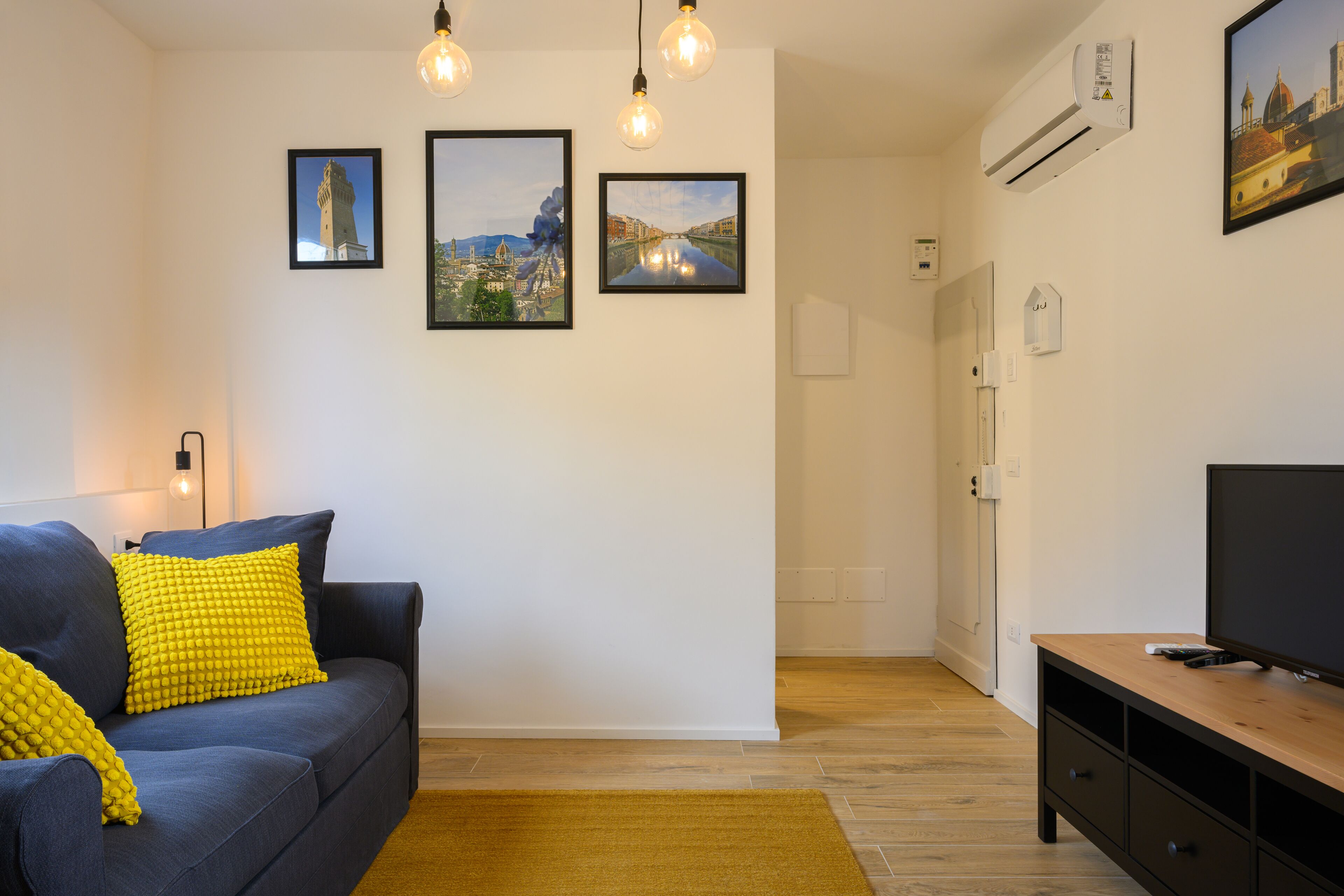 A living room with a sofa, a television, and a wooden entertainment unit.