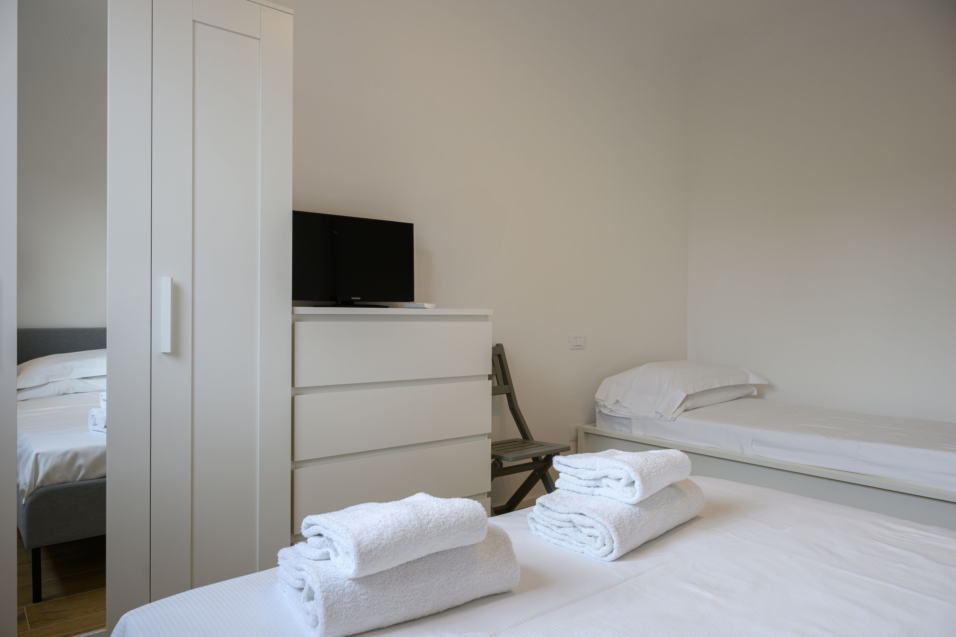 A hotel room with a bed, a chair, a desk, and a TV.