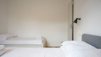 Een hotelkamer met twee bedden, een grijze hoofdbord en een wandlamp.