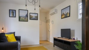 Uma sala de estar moderna com um sofá, um móvel de TV de madeira e um tapete amarelo.