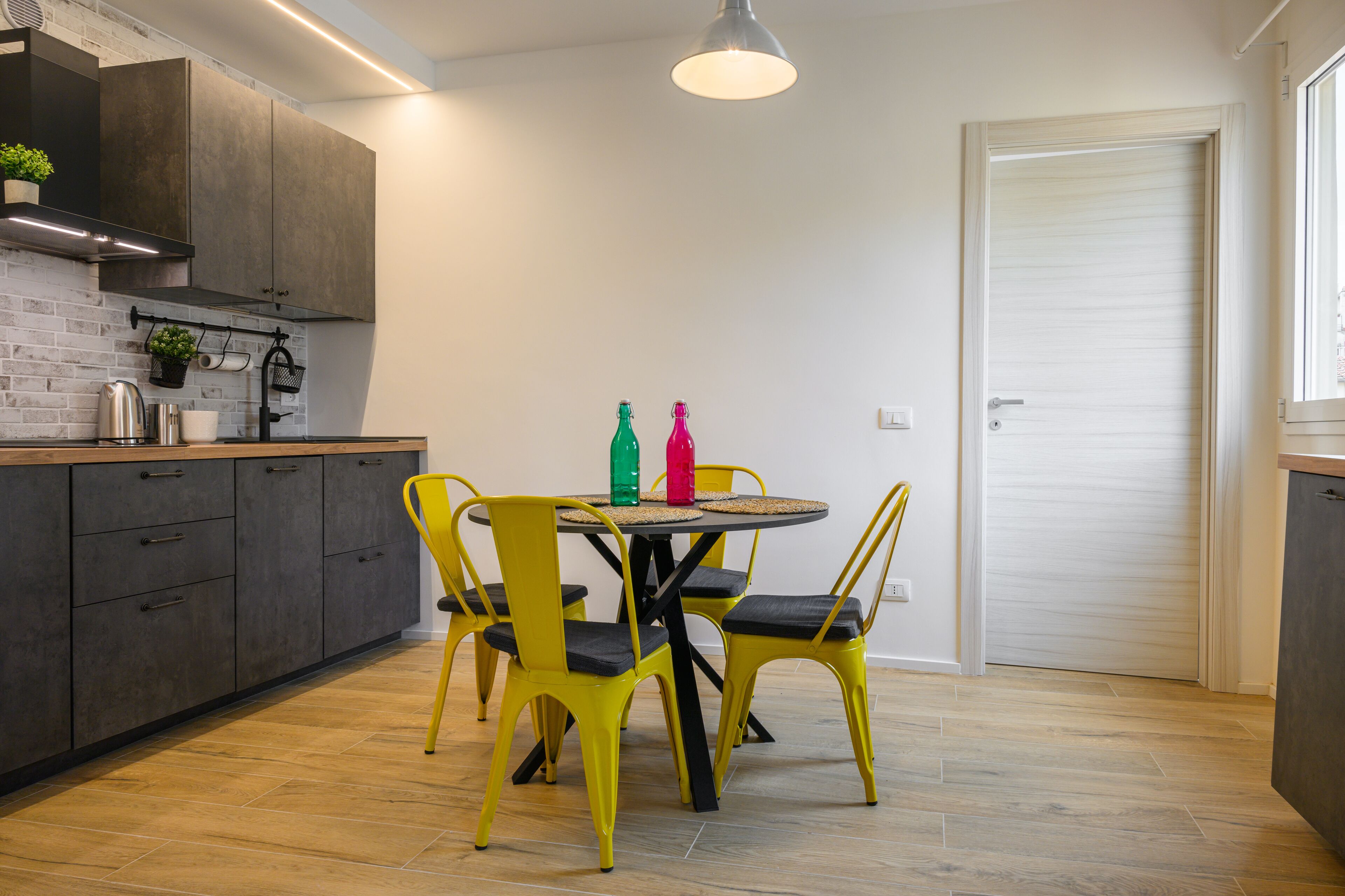 Una cocina pequeña con armarios oscuros, una mesa redonda y sillas amarillas.