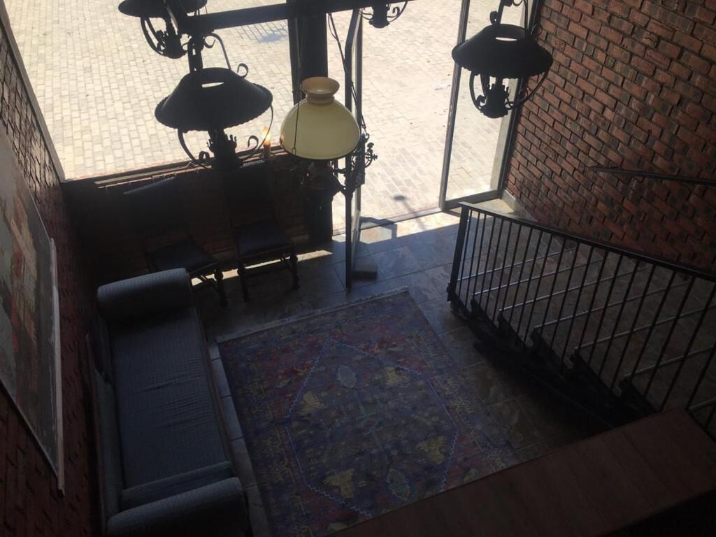 Un escalier orné d’un tapis à motifs, doté d’une rampe en métal et surmonté d’un luminaire suspendu.