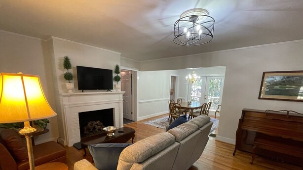 A living room with a sofa, a TV, a fireplace, a dining area, and a piano.
