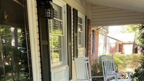 A brick porch with two rocking chairs and a welcome mat.