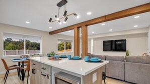A modern kitchen with a central island, wooden beams, and a large window offering a view of greenery. - Pacific Northwest Retreat Duplex 3min from Seattle by RedAwning (Tukwila)