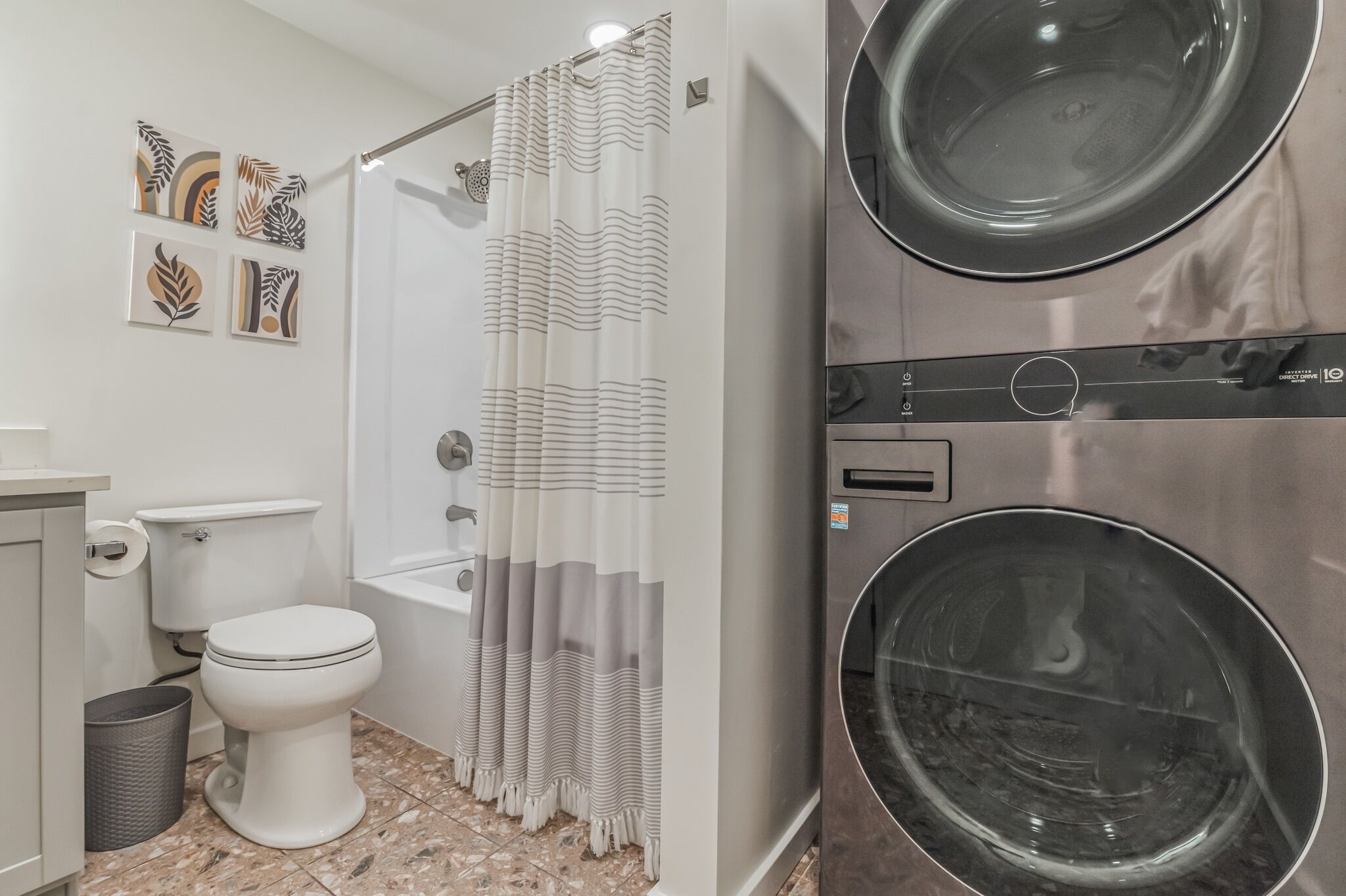 A bathroom with a toilet, shower, and a built-in washing machine.
