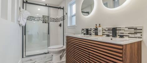 Une salle de bain moderne dotée d’une douche à parois de verre, de toilettes et d’un meuble-lavabo avec un motif en panneaux de bois.