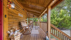 A wooden cabin with a porch, rocking chairs, and a decorative centerpiece. - *Relaxing 2BDR Getaway! HOT TUB + Arcade + XBox* (Sevierville)