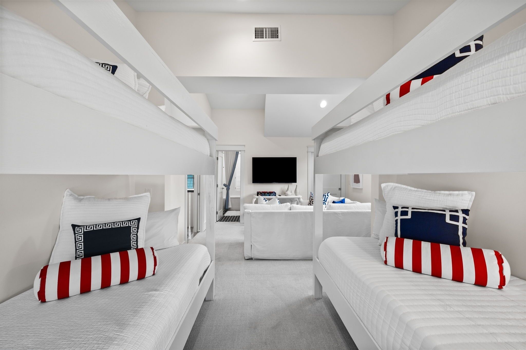 A modern hotel room with bunk beds, a flat-screen TV, a small kitchenette, and a bathroom with a shower.