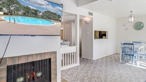 En rummelig opholdsstue med pejs, udsigt til poolen og et spiseområde med blå stole.