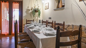 A dining area with a long table set for a meal, wooden chairs, a hanging plant, and a framed picture on the wall. - Scappo in Umbria, La casa verde di Eva (Amelia)